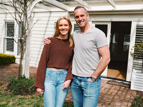 Father and teenage daughter stands close with each other smiling in the garden on a sunny day