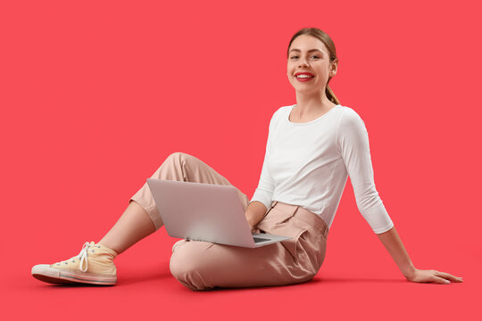 Female programmer with laptop sitting on red background