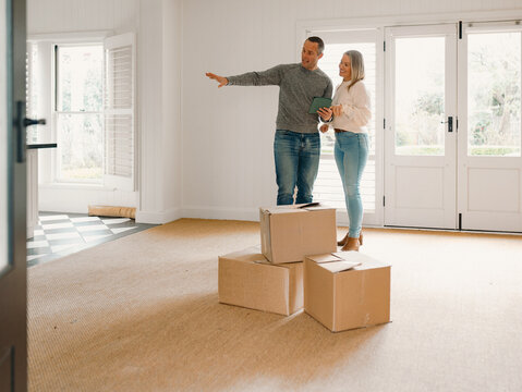 Couple standing behind boxes in an empty space of their new home planning