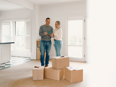 Couple standing behind boxes in an empty space of their new home planning