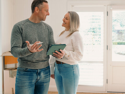 Couple standing in an empty space of their new home planning while looking at eachother