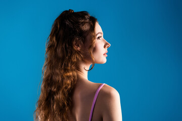 Young woman profile portrait with long hair and blue background looking thoughtful and elegant © deagreez