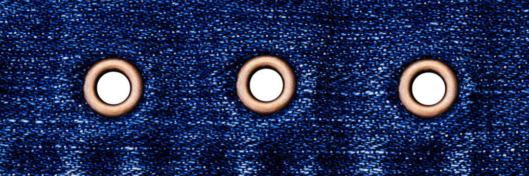 Denim fabric with metal grommets showing detail of stitching and holes for laces or fasteners at a clothing factory