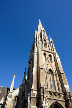 Looking up at a 19th century church steeple with clear blue sky.