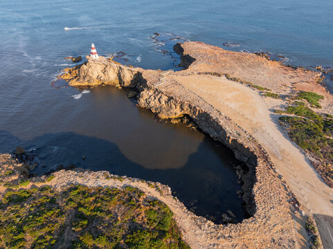 Aerial view of a monument high on a rocky cliff and eroded coastline