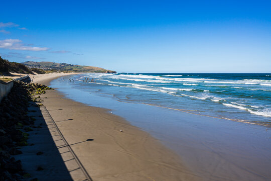 Early morning shadows on a sandy beach with surf waves, blue ocean and blue sky