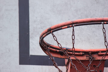 Detailed close up of a weathered basketball hoop rim with a durable chain net against a backboard © emerald17