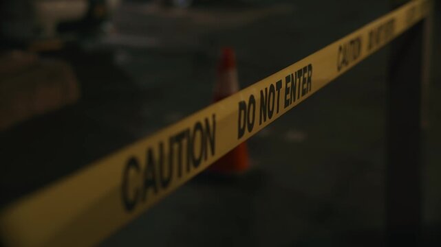 Yellow do not enter caution tape at night blocking access on parking creating sense of restricted territory and security control during dark nighttime environment