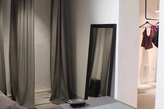 Empty fitting room with curtains and mirror in modern minimalist fashion boutique interior