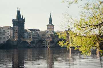 Fototapeta premium View of historic buildings near Charles Bridge in Prague during a sunny day with reflections in the water, spring