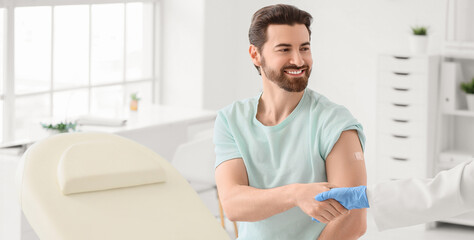 Young man with applied medical patch and doctor shaking hands after vaccination in clinic