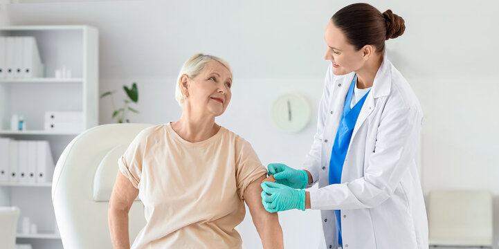 Senior woman receiving medical patch from doctor after vaccination in clinic