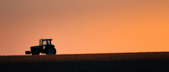 Fototapeta premium Tractor silhouette on farmland at sunset