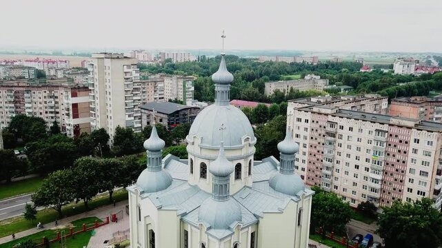 Orthodox cathedral dome with a cross surrounded by soviet-era residential buildings aerial view on an overcast day