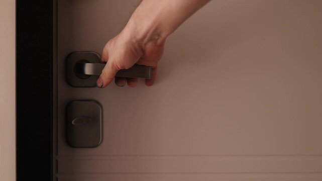 Close-up of a man's hand trying to open a locked door by pulling the handle. Shot of a person checking security or attempting to enter a secured room.