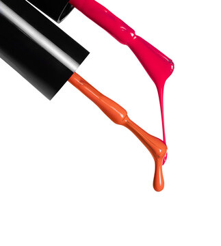 Two brushes with dripping nail polish in different colors close-up