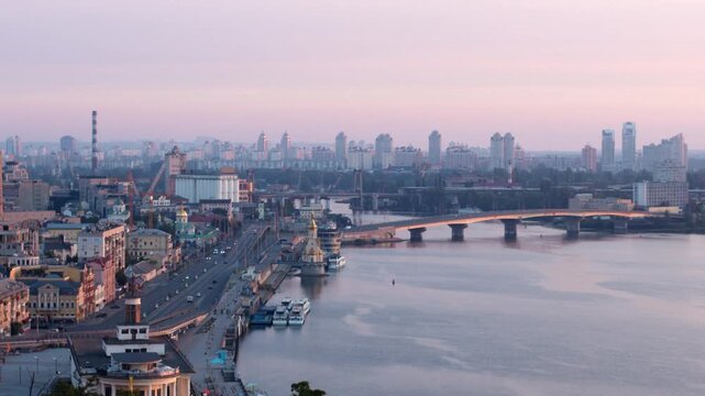 Aerial view of Kyiv city skyline and the Dnieper river during a beautiful sunrise, featuring the Podil neighborhood