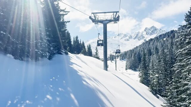 Scenic ski lift ride above snowy alpine slopes with skiers descending the mountain in Courchevel, France, featuring panoramic winter landscape and sunny blue sky in 