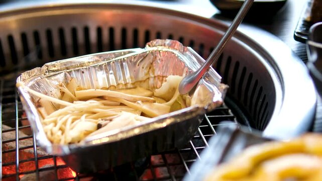 enoki mushrooms grilling on foil over charcoal korean bbq close up scene 