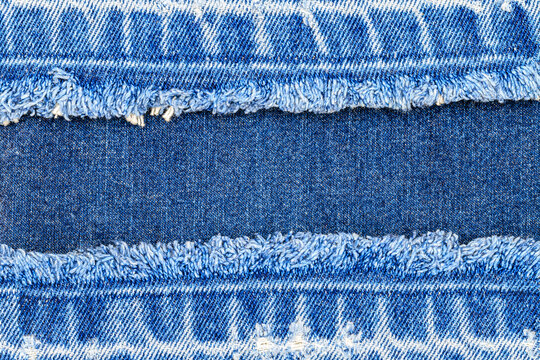 Denim fabric showing different blue shades and raw edges from fraying at midday under indoor light