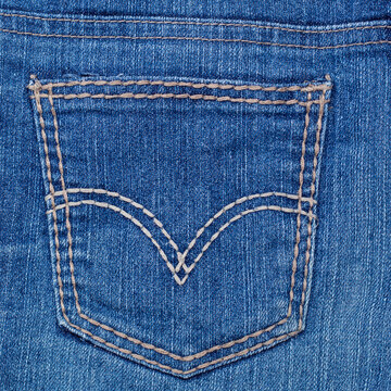 Close up view of back pocket of blue denim jeans with stitching pattern