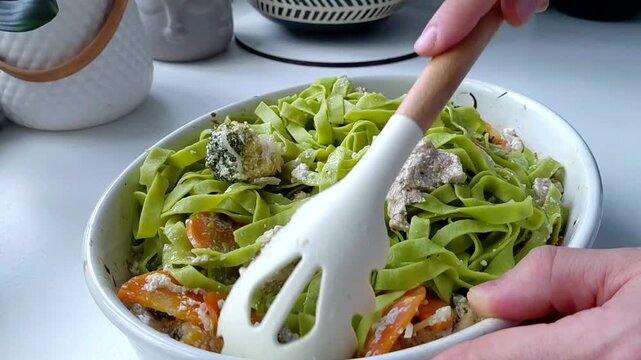Green tagliatelle pasta is mixed with baked vegetables and turkey in a creamy sauce.
