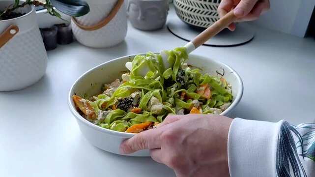 Green tagliatelle pasta is mixed with baked vegetables and turkey in a creamy sauce.