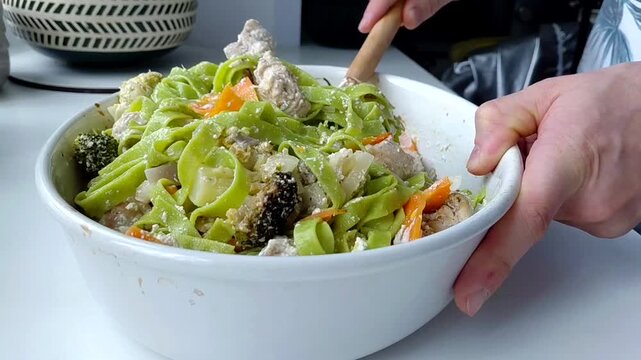 Green tagliatelle pasta is mixed with baked vegetables and turkey in a creamy sauce.