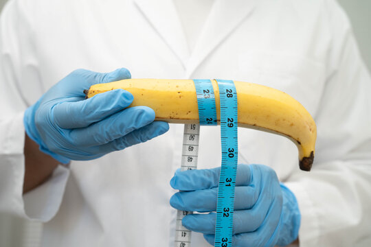 Male doctor stands holding a banana, penis health.