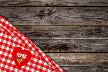 Obraz premium Checkered tablecloth with heart patch placed on rustic wooden table