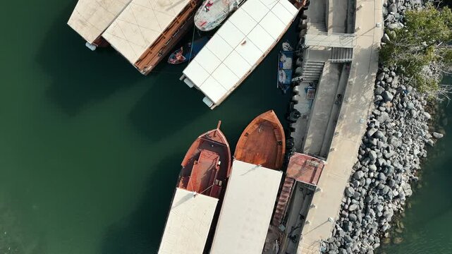 Cinematic Rotating Drone Fly-Up over Traditional Wooden Boats in Ein Gev Harbor Aerial of Sightseeing Vessels at the Sea of Galilee Marina 