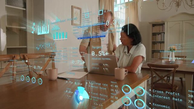 Older man placing mug circling dining table woman at laptop HUD charts reacting and reviewing funds