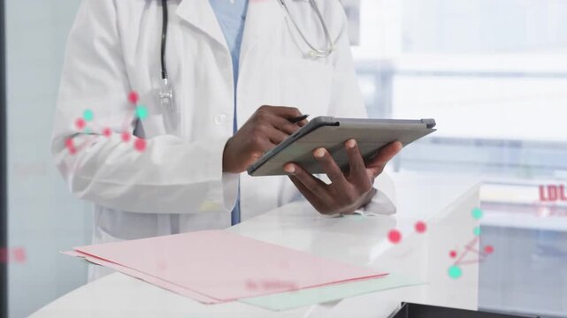 Doctor tapping tablet at desk using stylus starting SpO2 node overlays across chest checking vitals
