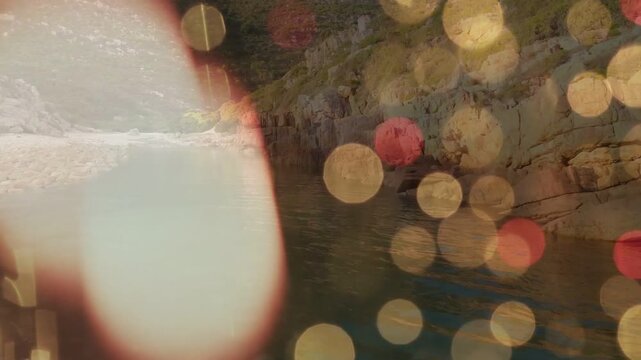 Fingertip approaching lens causing blur moving to center, occluding bokeh, revealing shore