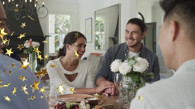 Couple holding hands at table, reacting to left speaker while gold stars overlaying for lifestyle