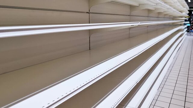 Empty shelves in a supermarket display the gradual lack of products, emphasizing the organized layout of the retail space and the absence of items
