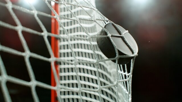An ice hockey puck hitting the back of the net