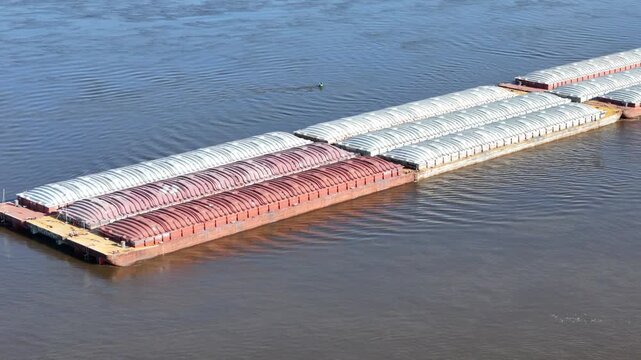 Panning view of a Tug boat pushing a large set of barges North up  the Mississippi River