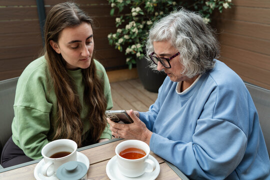 Senior woman learning smartphone technology from young adult