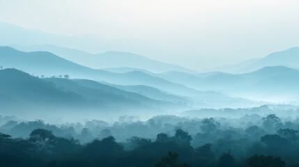 Naklejka premium Layers of blue mountain ranges fading into distant fog at sunrise. Panoramic landscape view of misty hills and forest valleys. Concept of travel, nature, tranquility and wilderness.