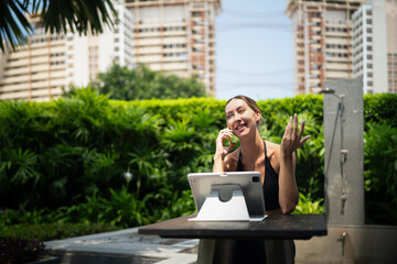 Fototapeta premium Attractive confident fit woman wearing sportswear using tablet pc computer and and speaking on phone urban park outside