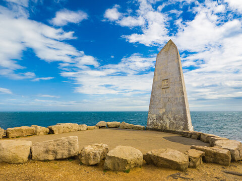 Historical stone obelisk monument serving as a coastal daymark standing against a blue sky with clouds (Portland, England, United Kingdom)