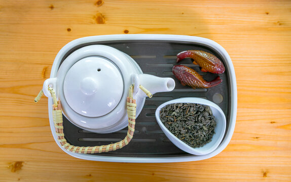 Traditional ceramic teapot with dry tea leaves and fish figurines on chaban tray, top view. Tea ceremony ritual for meditation and wellness. Zen lifestyle concept with healthy oriental tea