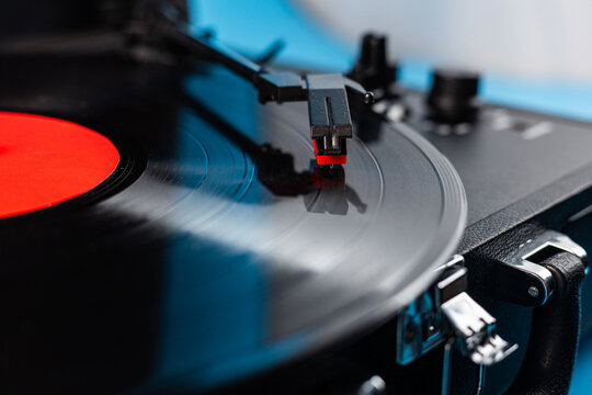 Close-up of a vintage record player needle on a spinning vinyl disc with a red label