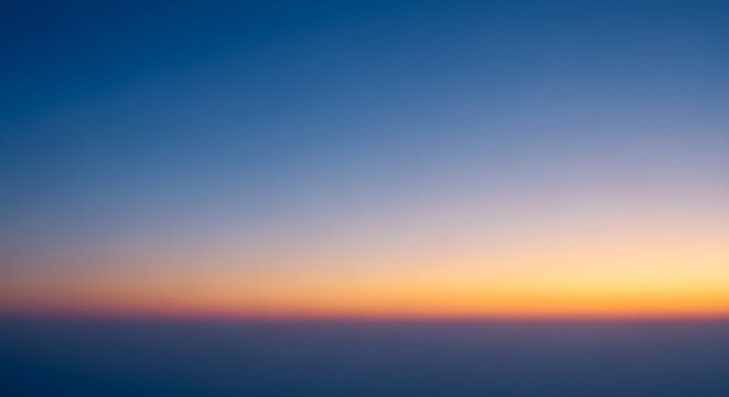 Abstract sunset gradient background with soft transition from deep blue to orange and purple, minimalist atmospheric sky texture for design