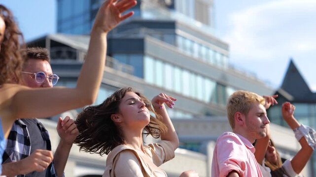 Happy friends standing in a row and dancing while jumping and holding their hands up at open air party on the roof. Real time