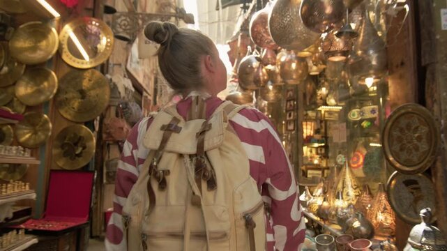 Woman tourist walking along narrow alley of oriental bazaar on sunny day
