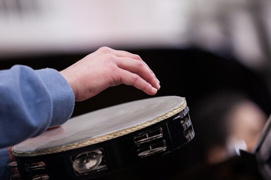 Close-up of a musician's hand playing a tambourine
