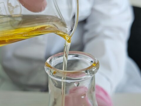 Liquid being poured into a glass flask during a science experiment in a lab