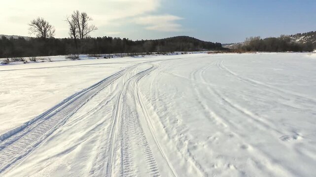Icy River Bordered By Rocky Edges And Footprints. Frozen Waterway With Snow Formations And Rugged Rock Borders. Snowcovered River With Winding Tracks And Steep Rocky Cliffs On Each Side